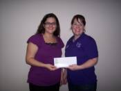 TBL volunteer Sommer Dunston presents ACS Staff Partner Emily LaMontagne with a $1,525 check to the American Cancer Society.
